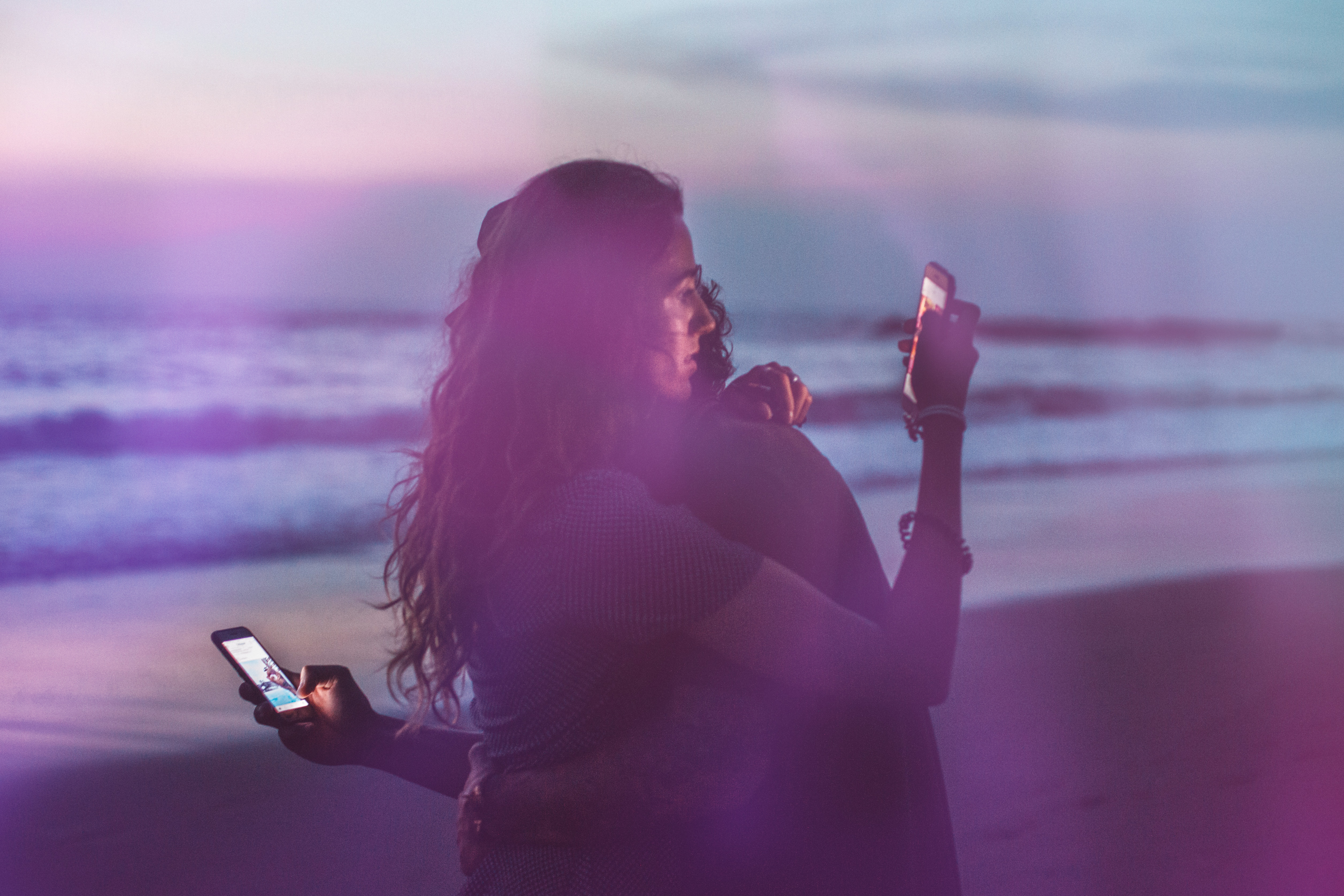women using phones on a beach